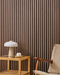 Teak NORDAN acoustic slat wood wall panels installed as a feature wall in a reading corner.