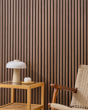 Teak NORDAN acoustic slat wood wall panels installed as a feature wall in a reading corner.